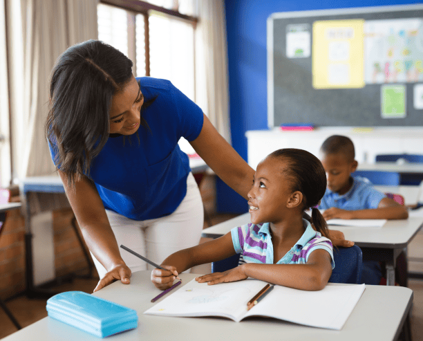 Teacher Smiling Helping Student With Writing
