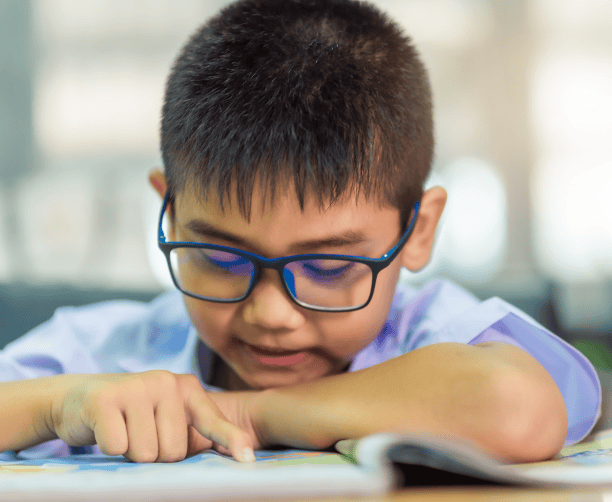 Young Boy Reading Book With Glasses