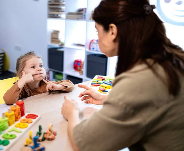 Preschool Child Practicing Facial Expressions With Educator