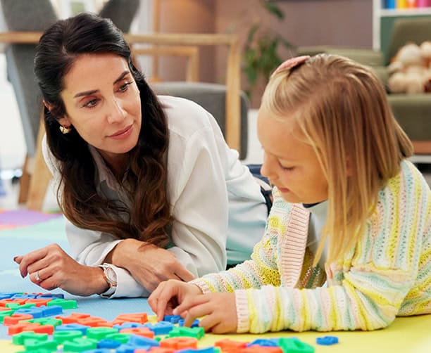 Preschool Teacher Helping Child Practice Letter Recognition